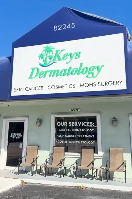 The Islamorada office at 82245 Overseas Highway: a blue awning sign reading "Keys Dermatology — Skin Cancer, Cosmetics, Mohs Surgery" above a pale green front with four chairs on the porch, and window lettering listing "Our Services: General Dermatology, Skin Cancer Treatment, Cosmetic Dermatology"
