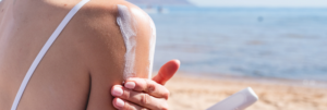 A shoulder with white sunscreen being rubbed in, the sea behind