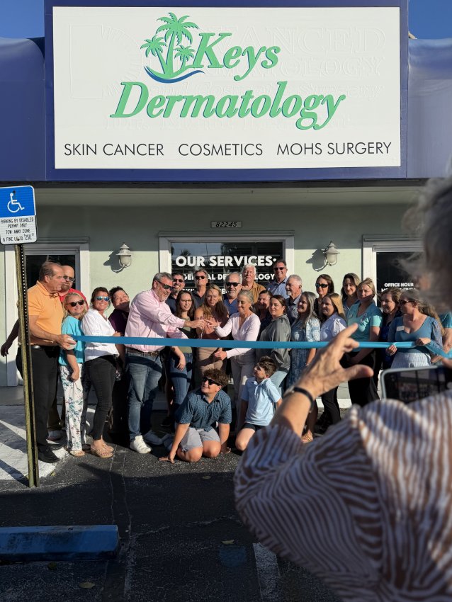 Staff and guests gathered at the Keys Dermatology entrance behind a blue ribbon