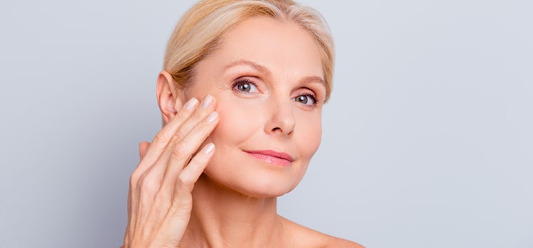 an older woman touching the smoothness on her cheek