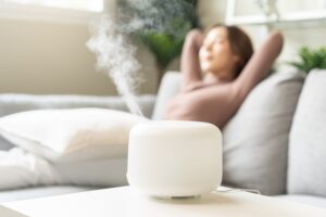 Modern air humidifier during relax or rest, happy blurred asian young woman
